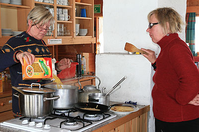 Sigbritt och Marie vid spisen i Olavsbu