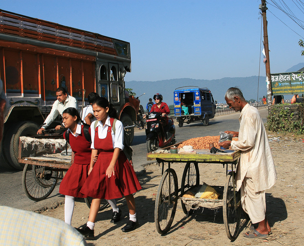 School girls in uniform. A man selling nuts.